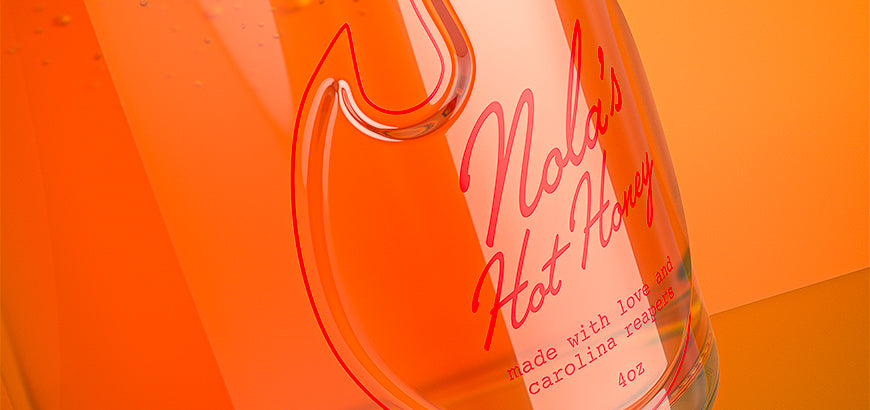 Clear glass jar with detailed branding, featuring an orange backdrop to highlight its sleek and durable construction.