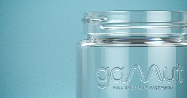 A close-up of small glass jar with raised lettering and logo embedded into the glass surface.
