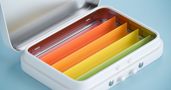 A closeup of a small tin container with the lid open showing custom color-coded paper inserts for organization.